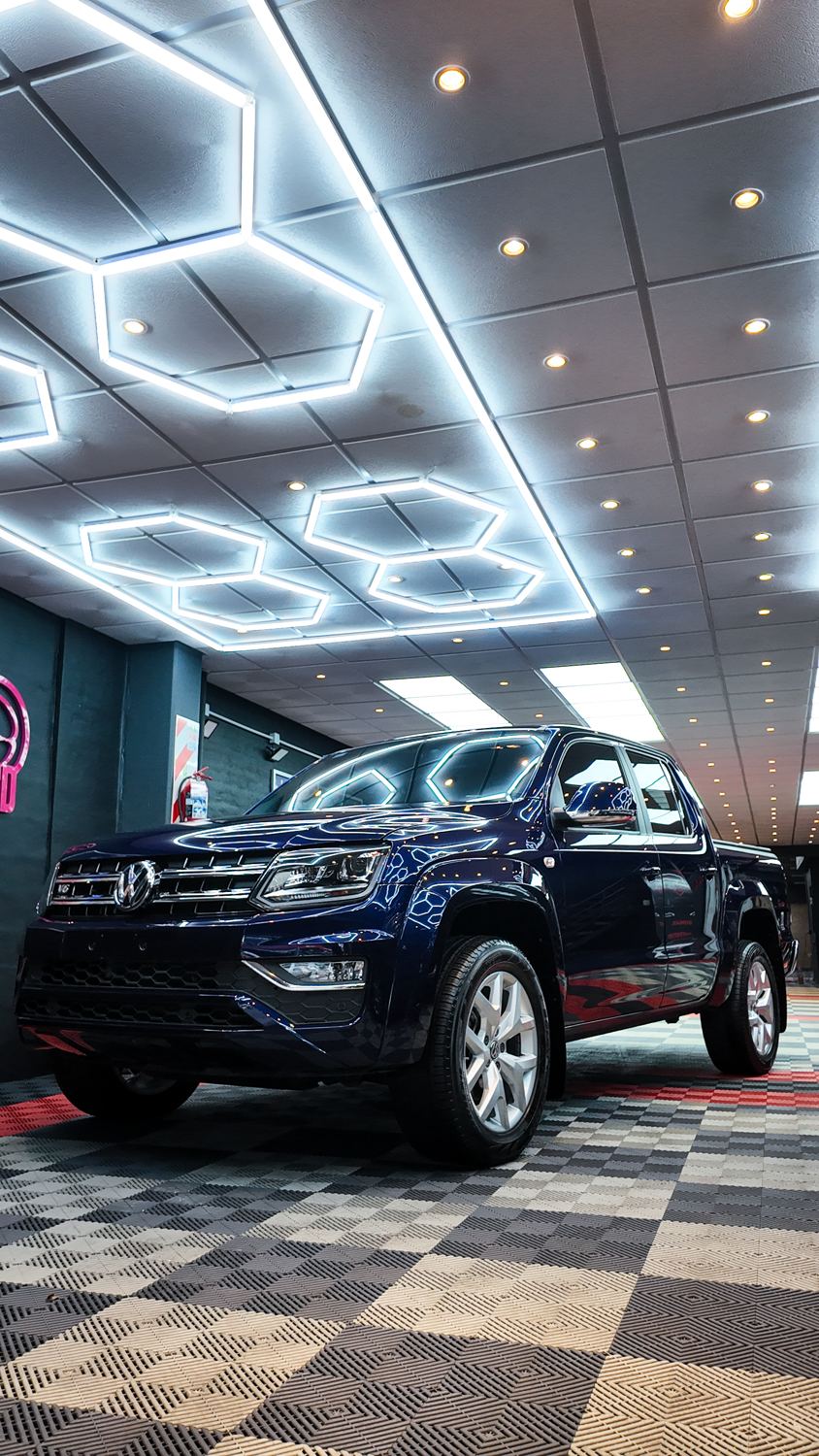 Volkswagen Amarok azul oscuro brillando bajo las luces del taller de HGC
