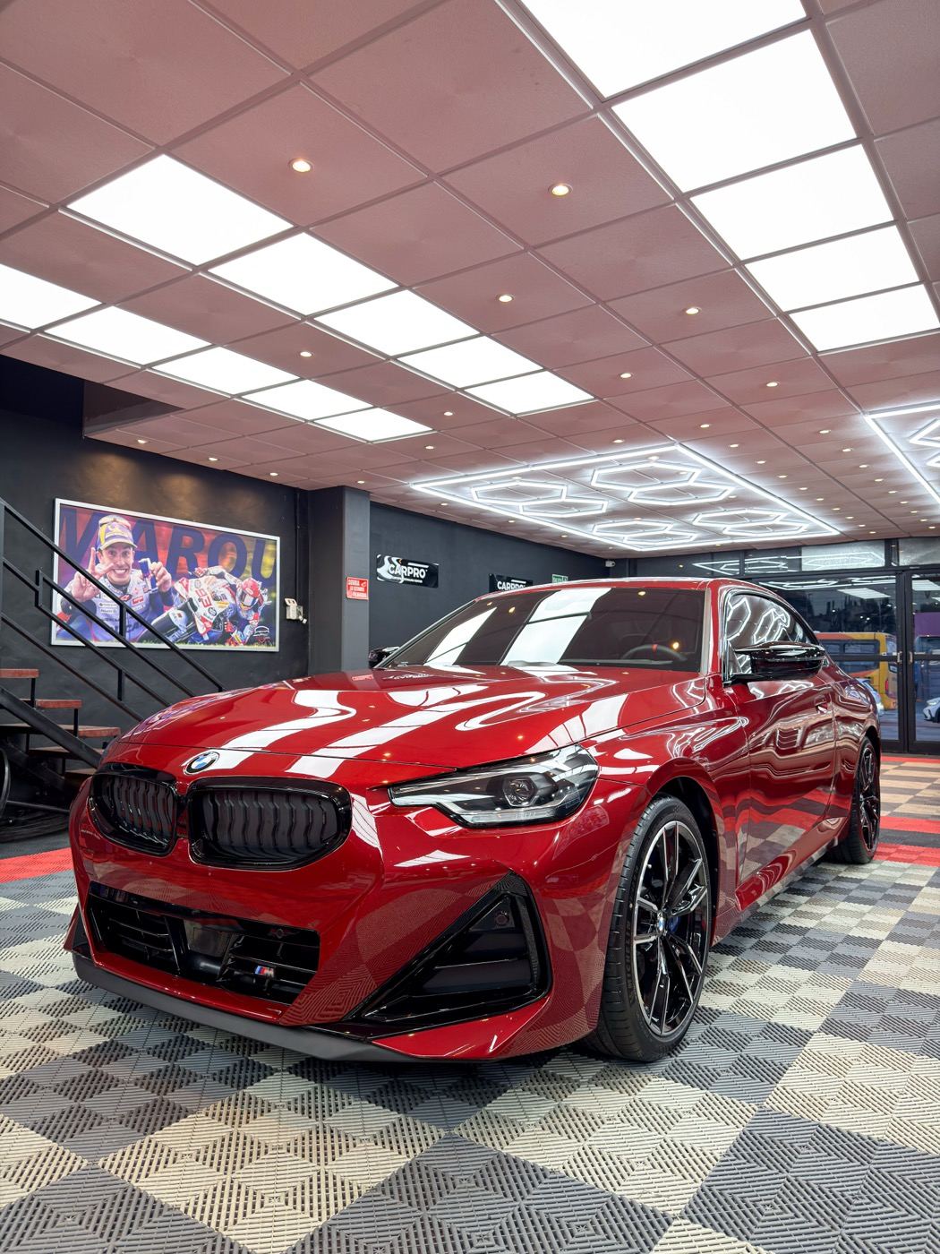 BMW rojo de frente en el taller de HGC, con el parabrisas protegido